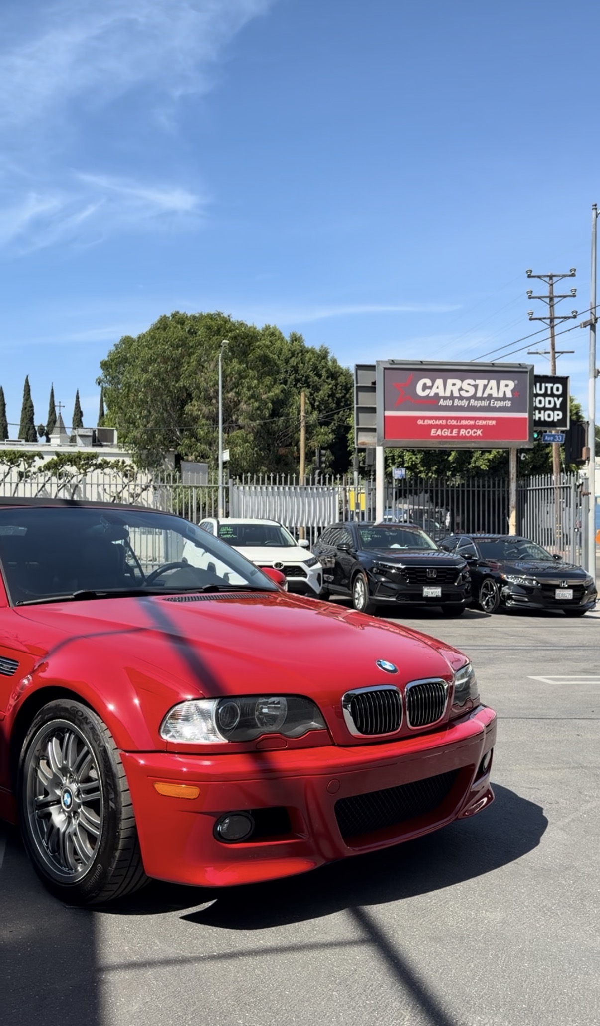 Red BMW with the CARSTAR Eagle Rock shop sign in the background